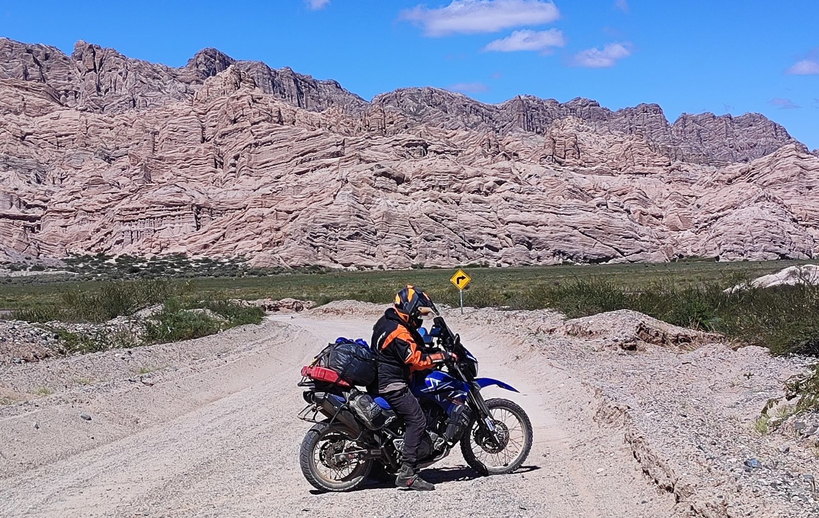 Motociclista en un camino de ripio entre cerros de roca, en Antofagasta de la Sierra