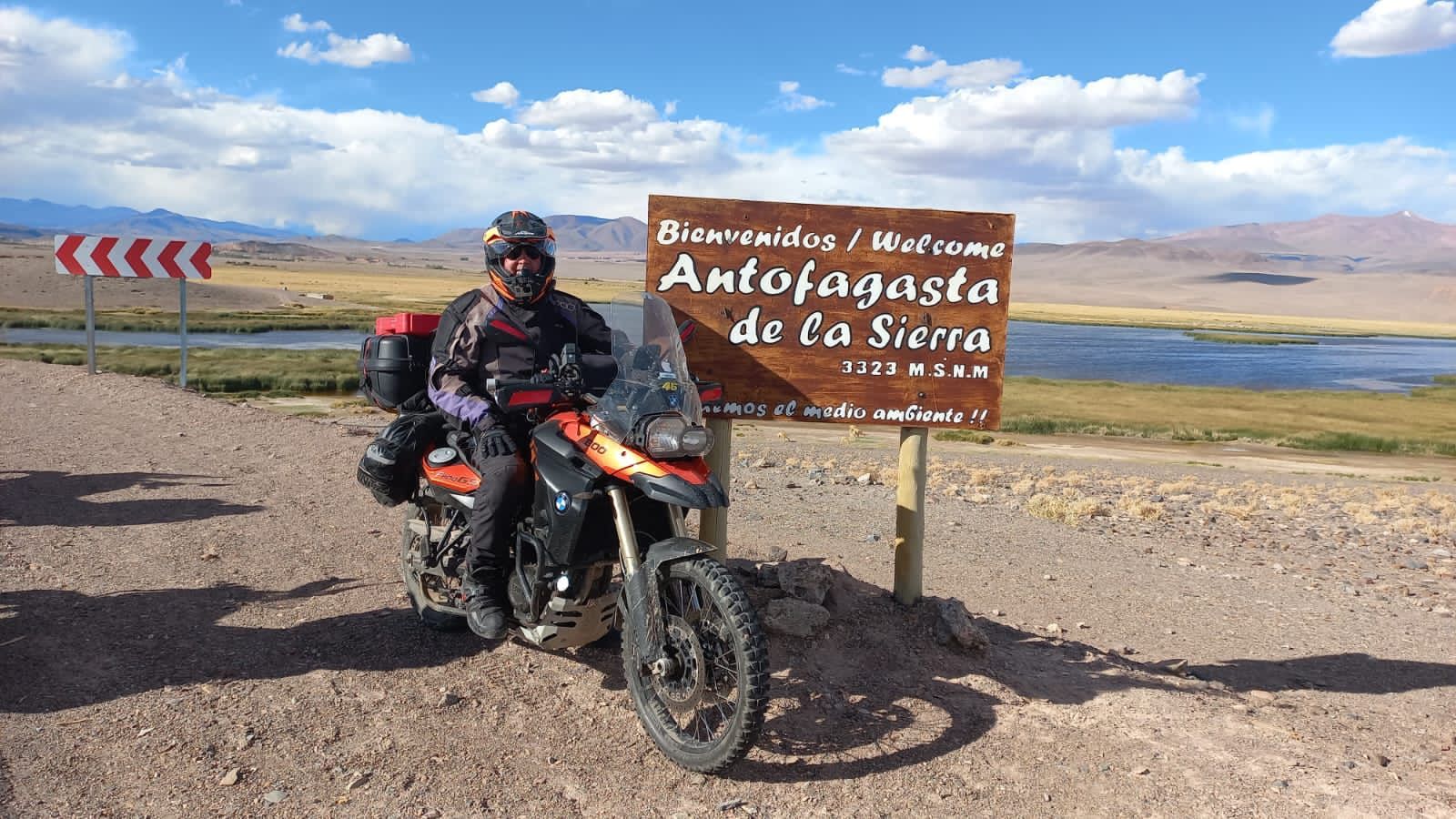 Motociclista junto al cartel de bienvenida a Antofagasta de la Sierra, Catamarca, a 3323 metros